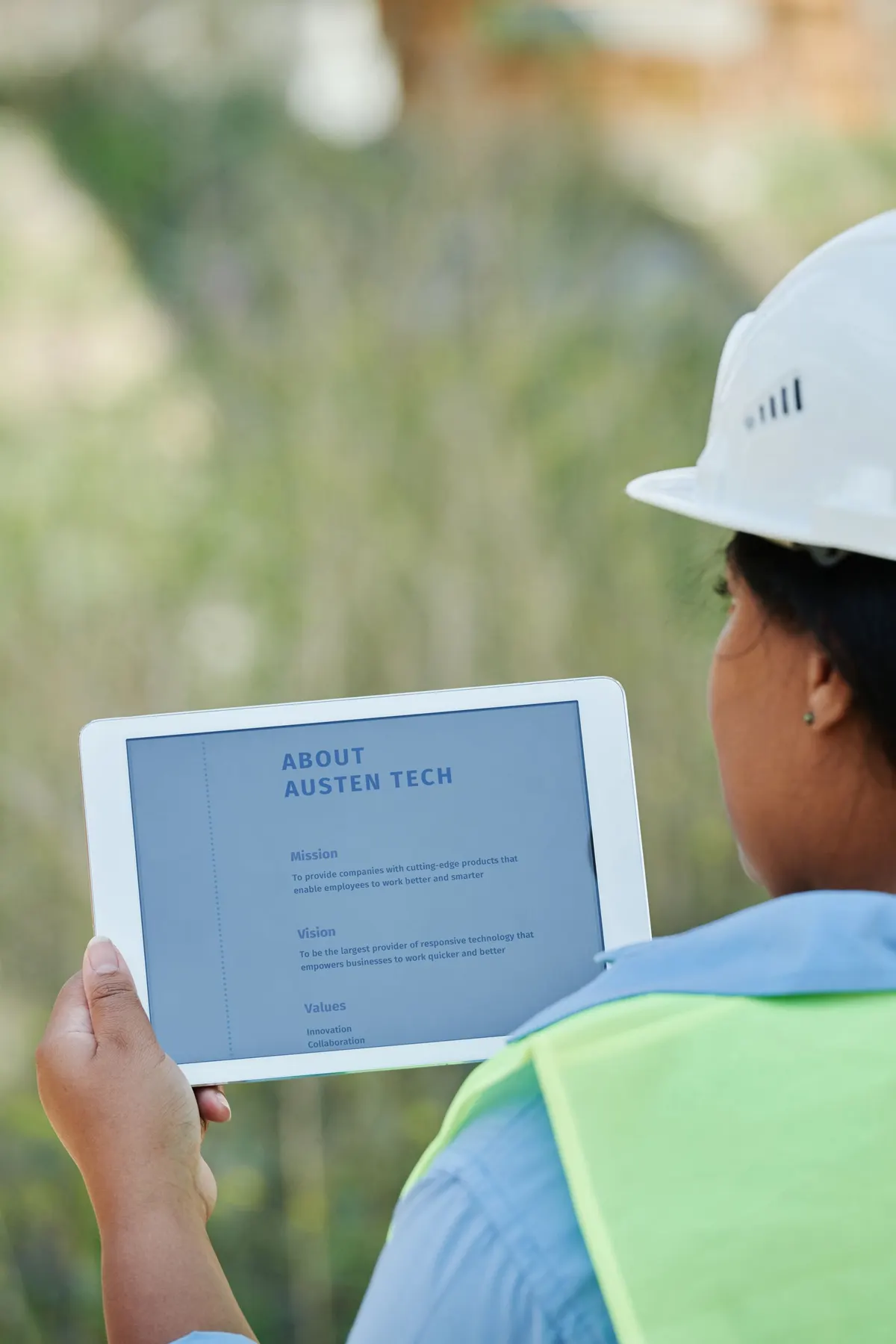 Monteur bekijkt gegevens op een tablet op een bouwlocatie.