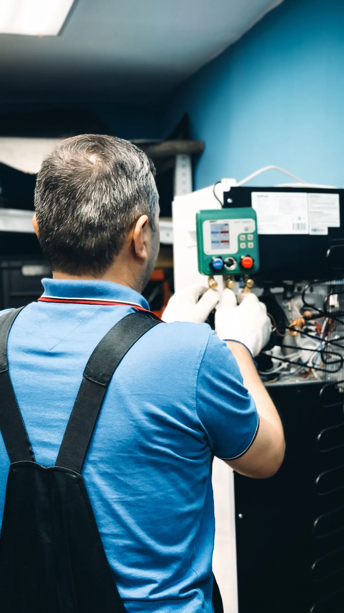 Monteur voert onderhoud uit aan de binnenunit van een airconditioningsysteem met een digitale meter.
